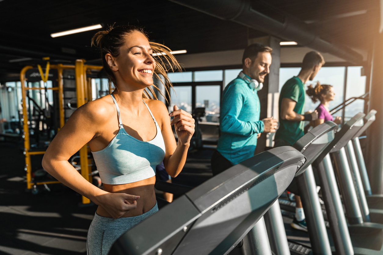 Happy athletic people jogging on treadmills in a health club