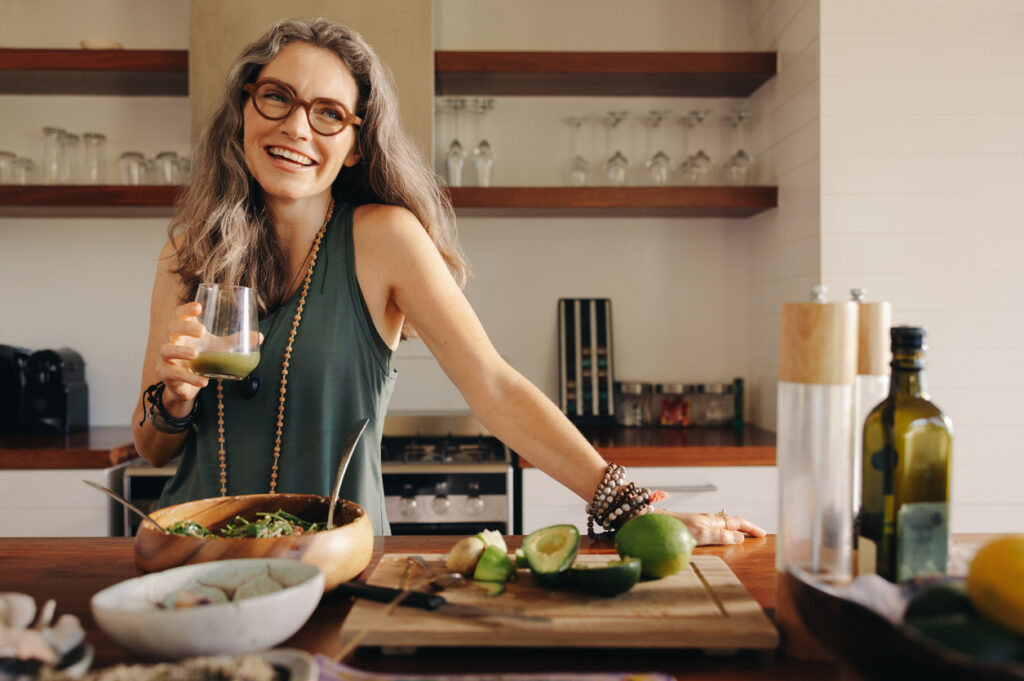 Happy middle-aged woman with graying hair in the kitchen smiling. Learn how menopause can cause hair loss. 