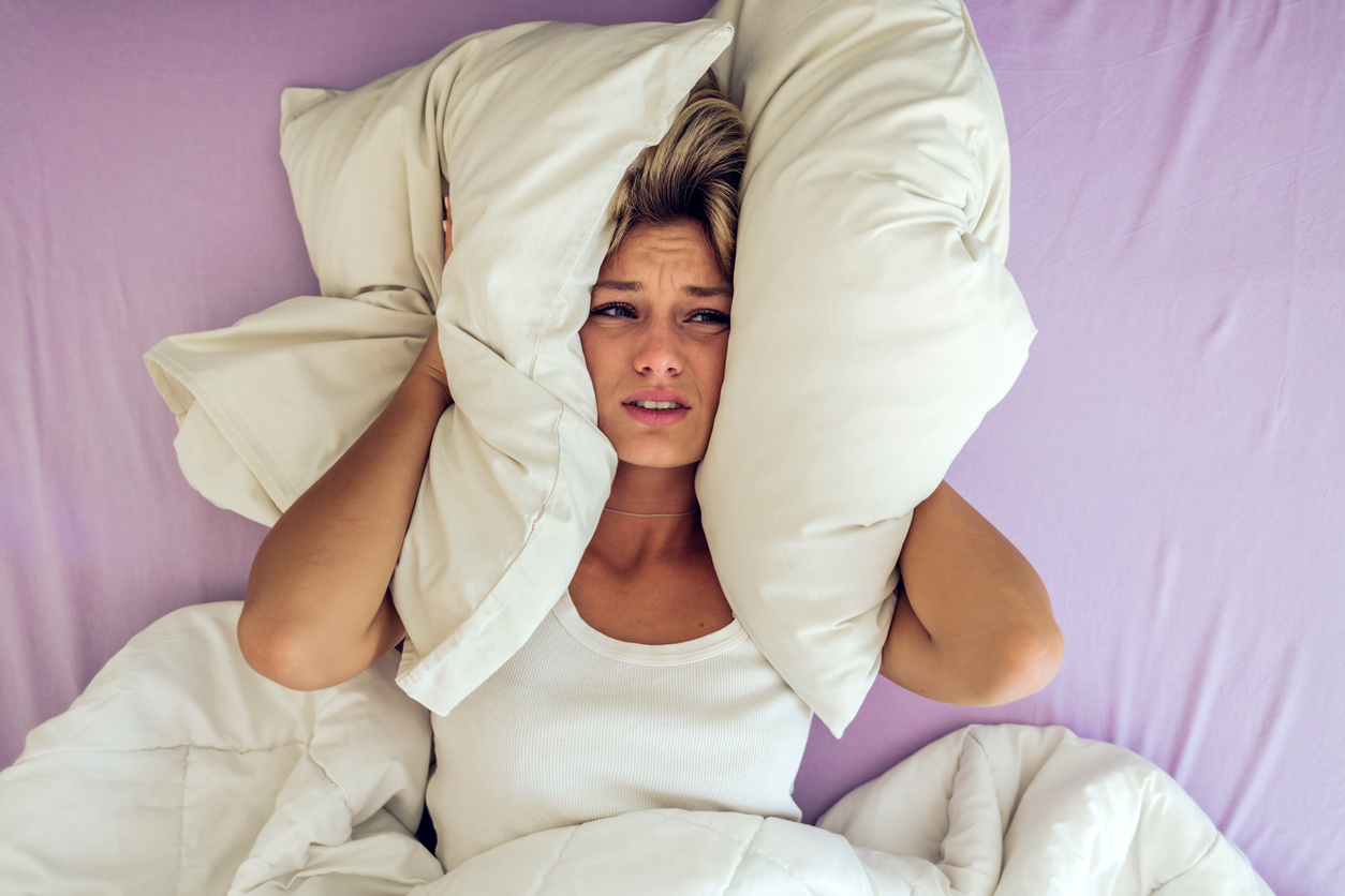 woman in her 40s lying in bed desperate about what causes night sweats. Find out what nobody tells you about night sweats.